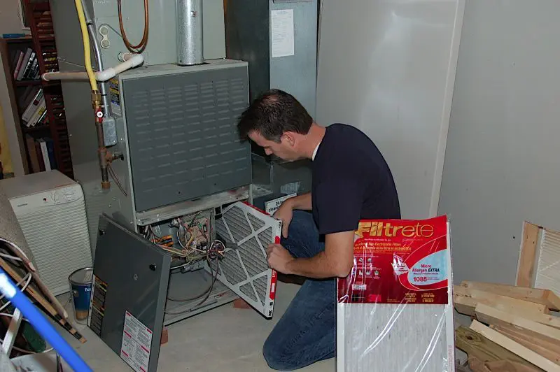 man performs heating system maintenance