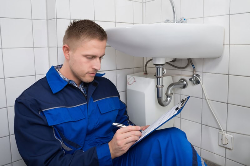Gelinas' plumber going through his plumbing maintenance checklist while underneath bathroom sink.