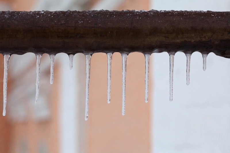 What Should I Do to Fix Frozen Pipes? Icicles hanging from a brown pipe.